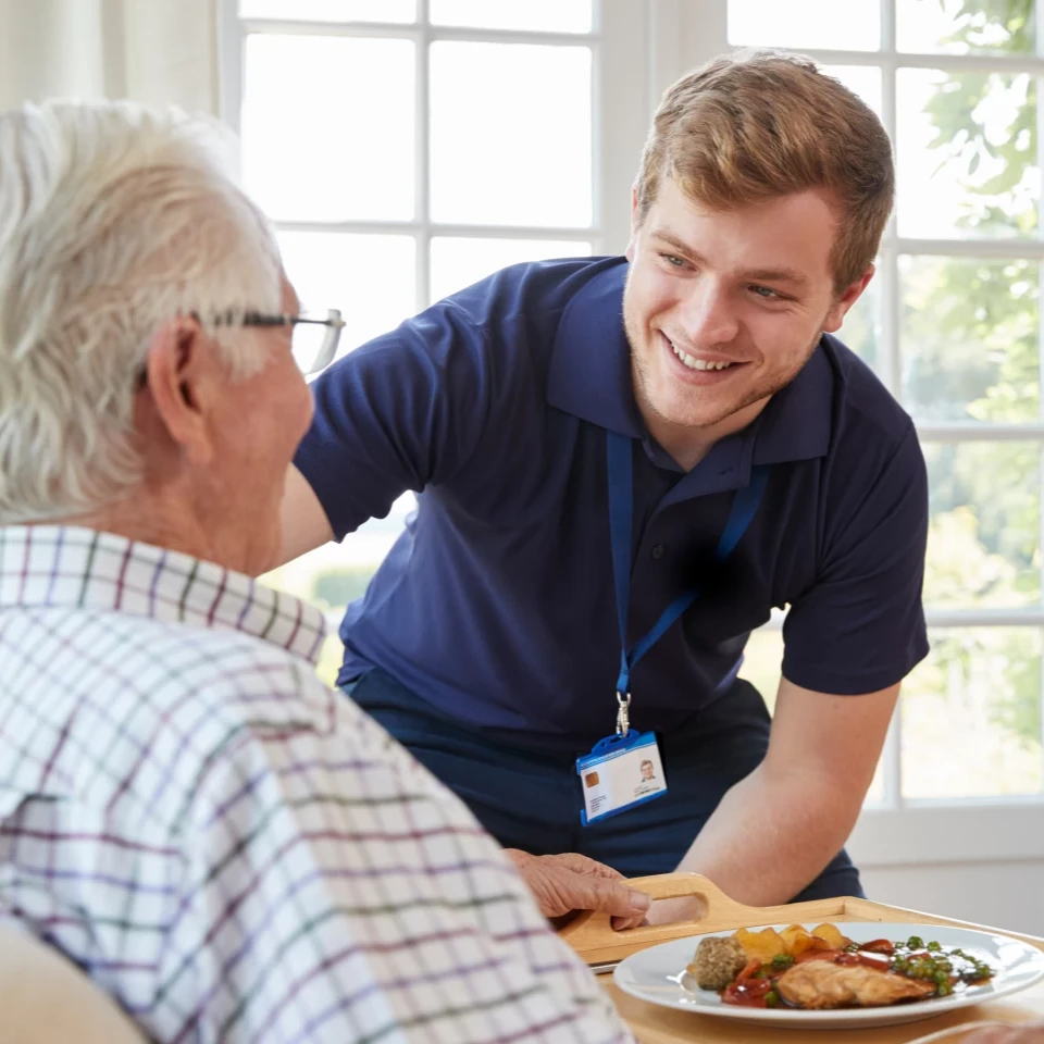 A caregiver helping an older adult at mealtime